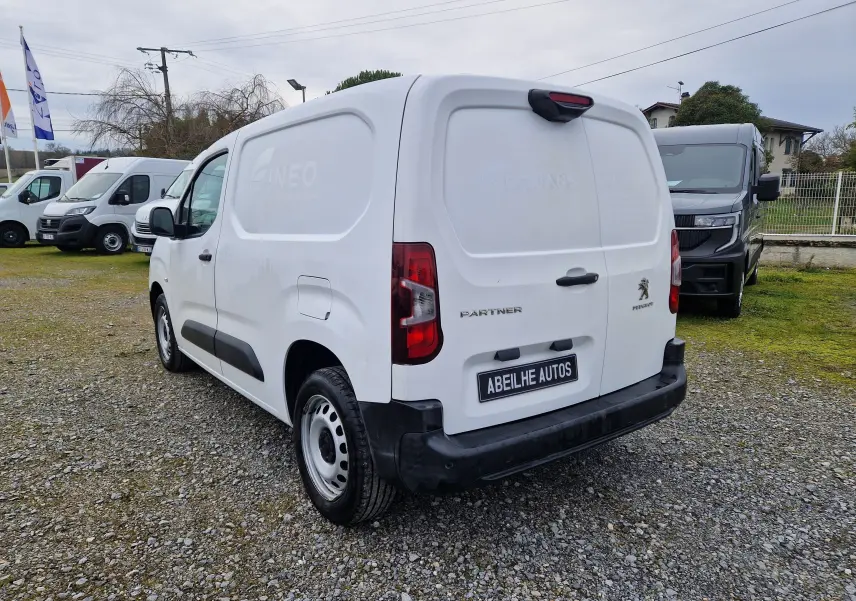 Vue 3/4 arrière droite d'un utilitaire Peugeot Partner blanc 2020 avec marquage et pare-chocs noirs sur un parking.
