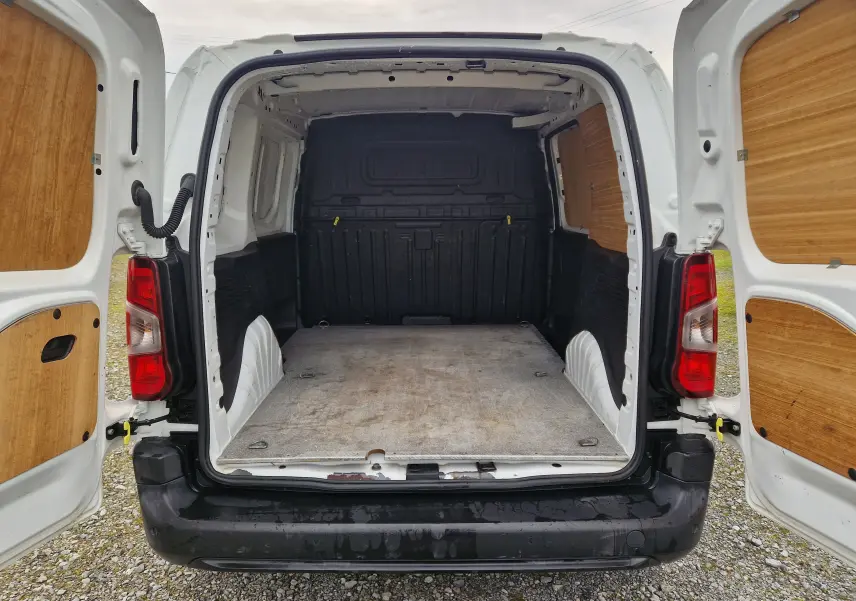 Vue arrière du Peugeot Partner blanc 2020 avec portes ouvertes, montrant l'espace de chargement vide et revêtement bois.