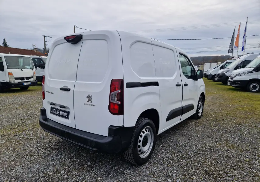 Vue 3/4 arrière droite d'un Peugeot Partner blanc 2020 utilitaire avec portes arrière battantes et protections latérales noires.