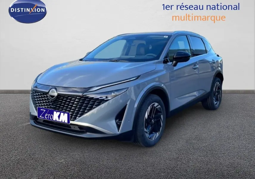 Vue 3/4 avant droit d'un Nissan Qashqai 2025 gris argile métallisé avec calandre noire et jantes foncées.