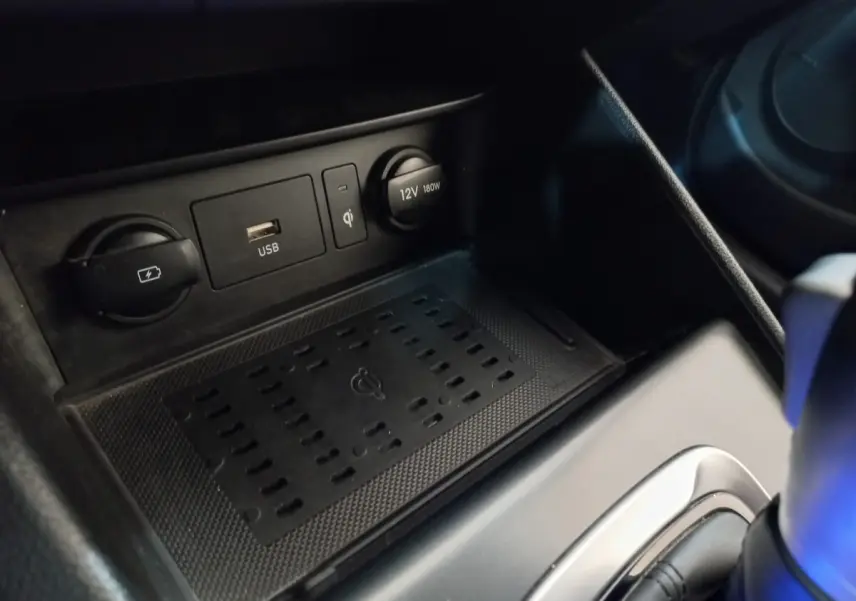 Gros plan sur la console centrale du Hyundai Kona gris foncé montrant prises USB, 12V et recharge sans fil.