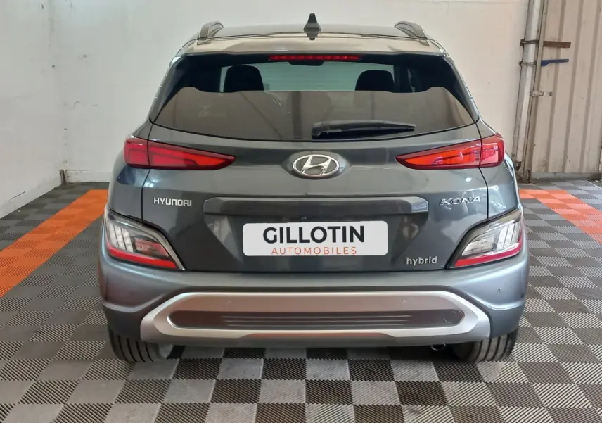 Vue arrière d'un Hyundai Kona gris foncé hybride 2022 avec feux LED et logo visible sur un sol damier noir et orange.