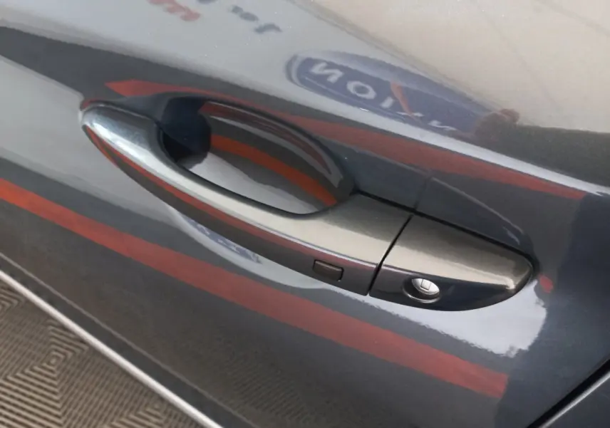 Poignée de porte côté gauche gris foncé du Hyundai Kona 2022, avec bouton de déverrouillage intégré.