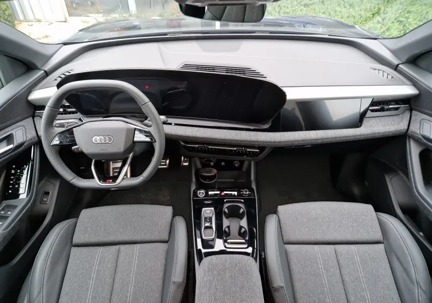 Vue intérieure de face de l'Audi Q6 e-tron Performance S-Line 2025, tableau de bord moderne et sièges gris Manhattan.