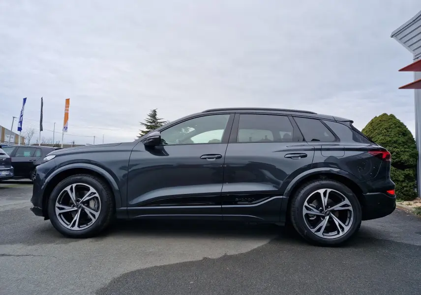 Profil côté gauche de l'Audi Q6 e-tron Performance S-Line gris Manhattan 2025, avec jantes sport et lignes épurées.