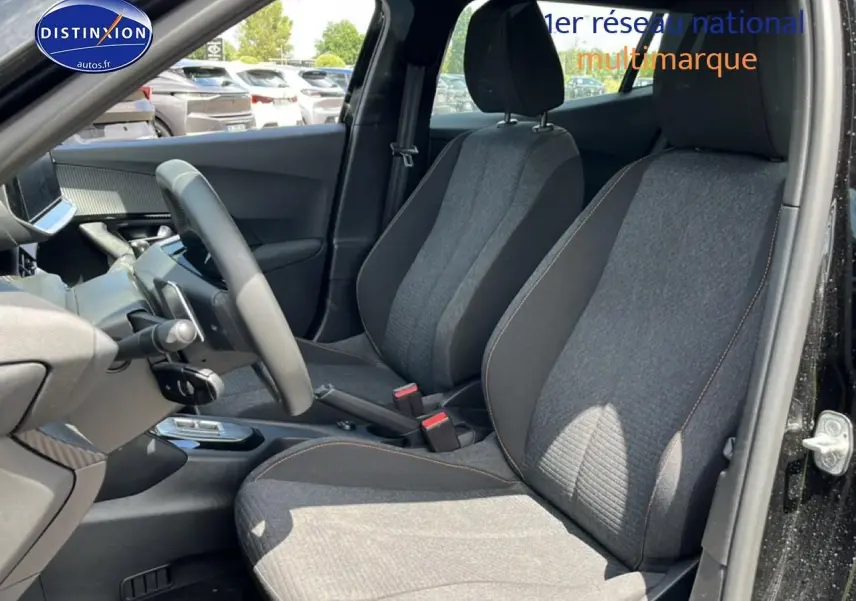 Vue intérieure côté conducteur de la PEUGEOT 2008 noire, montrant les sièges avant en tissu gris et le volant multifonction.