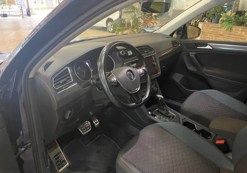 Intérieur noir du Volkswagen Tiguan 2020 vu côté conducteur, avec volant cuir et console centrale équipée.