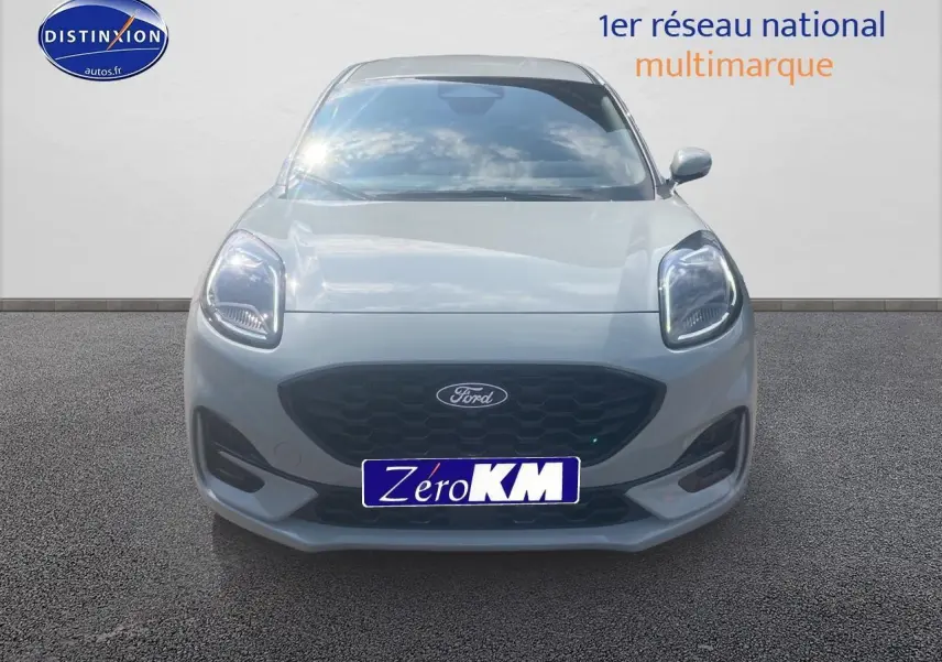 Vue frontale d'une Ford Puma gris cactus 2025 avec calandre noire et phares LED allumés.