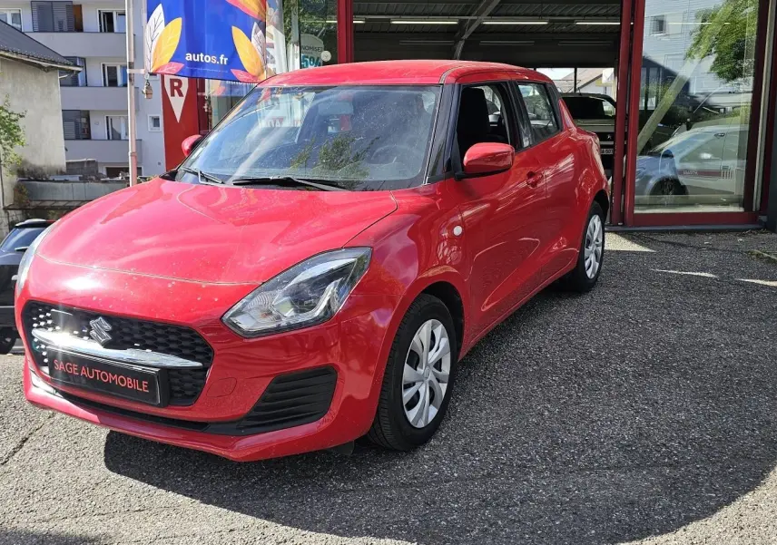 Suzuki Swift 1.2 Dualjet Hybrid rouge fervent vue 3/4 avant droit sur parking extérieur.