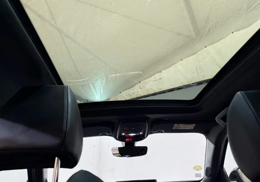 Vue intérieure du toit ouvrant panoramique et des sièges avant en cuir noir du Peugeot 2008 GT Pack bleu de 2021.