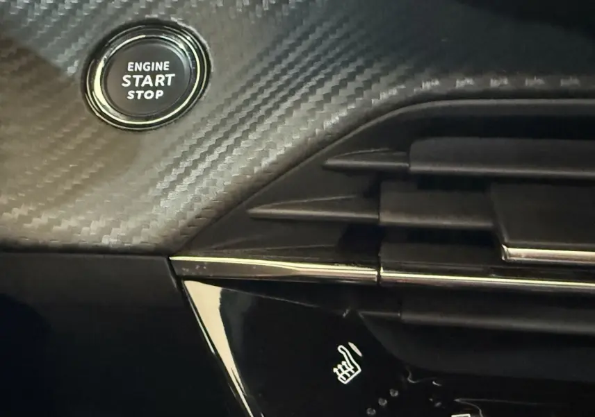 Détail intérieur du tableau de bord noir avec bouton start/stop et commande de siège chauffant du Peugeot 2008 GT Pack 2021.