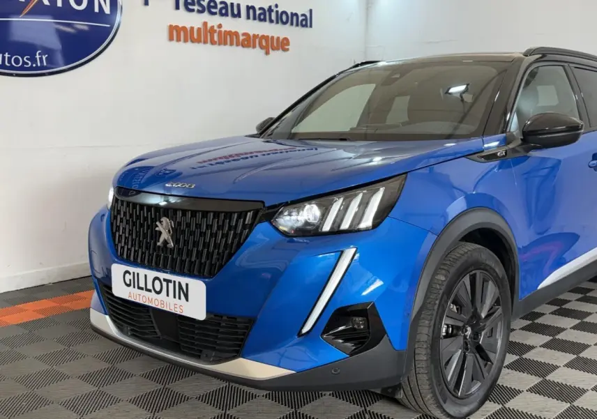 Vue 3/4 avant droit d'un Peugeot 2008 Bleu GT Pack 2021 avec calandre noire et phares LED distinctifs.
