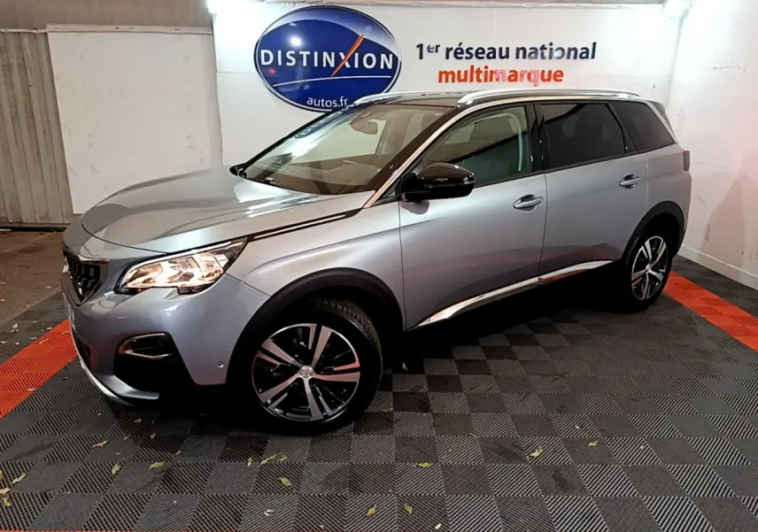 Peugeot 5008 gris clair vue 3/4 avant droit, avec jantes alliage et rétroviseurs noirs brillants.
