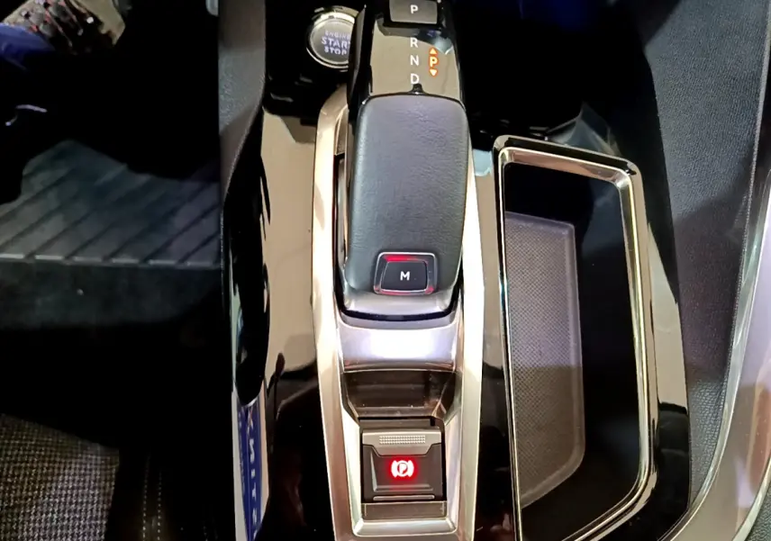 Le levier de vitesse automatique noir et chrome du Peugeot 5008 2020 avec bouton de frein à main électrique allumé.