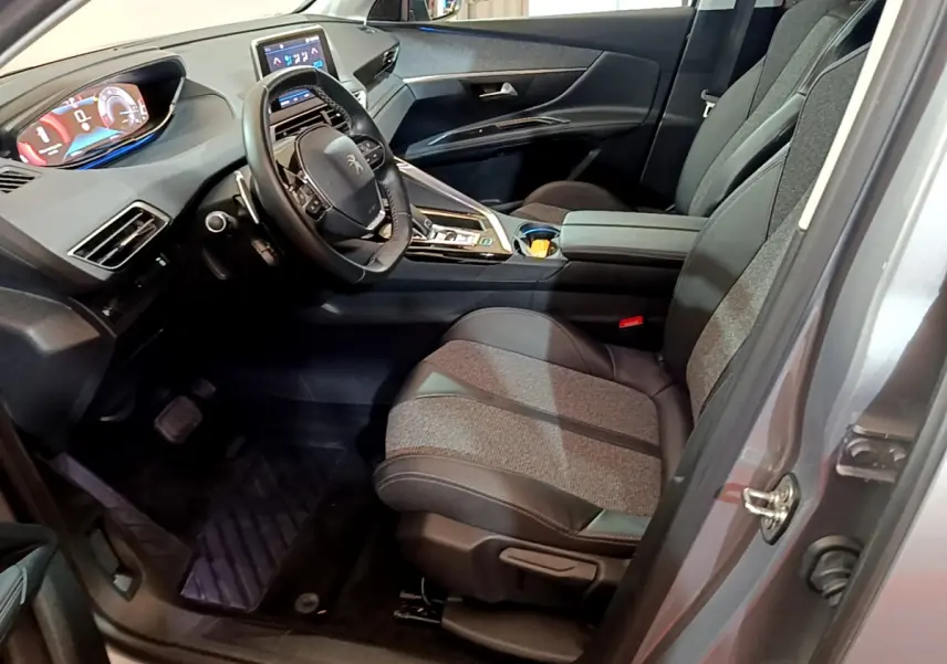 Intérieur avant droit du Peugeot 5008 gris clair, sièges tissu-cuir, tableau de bord numérique et écran tactile central.