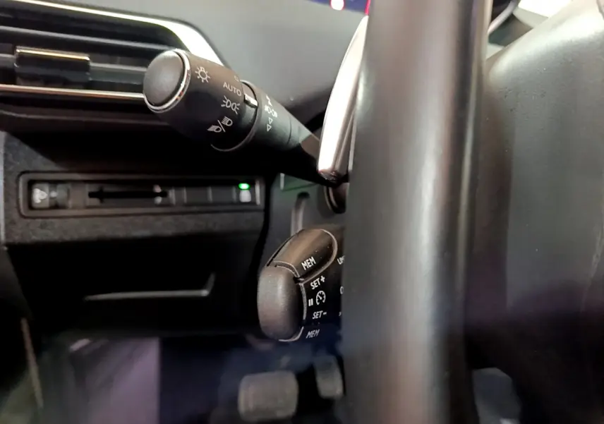 Gros plan sur les commandes au volant et le commodo d'éclairage du Peugeot 5008 gris clair, version 2020 Allure.