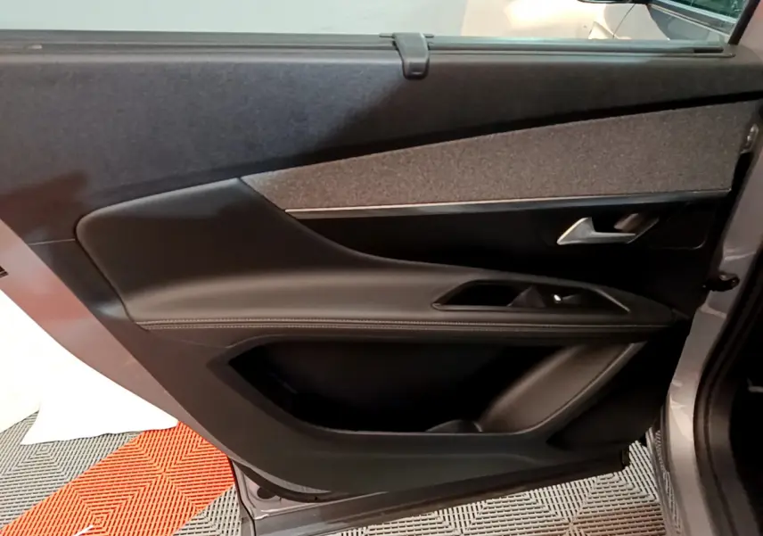 Gros plan sur la porte arrière droite gris clair du Peugeot 5008 avec garniture noire et insert tissu gris foncé.