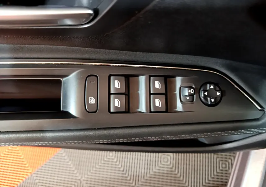 Gros plan sur les commandes de lève-vitres et réglage des rétroviseurs côté conducteur du Peugeot 5008 gris clair.