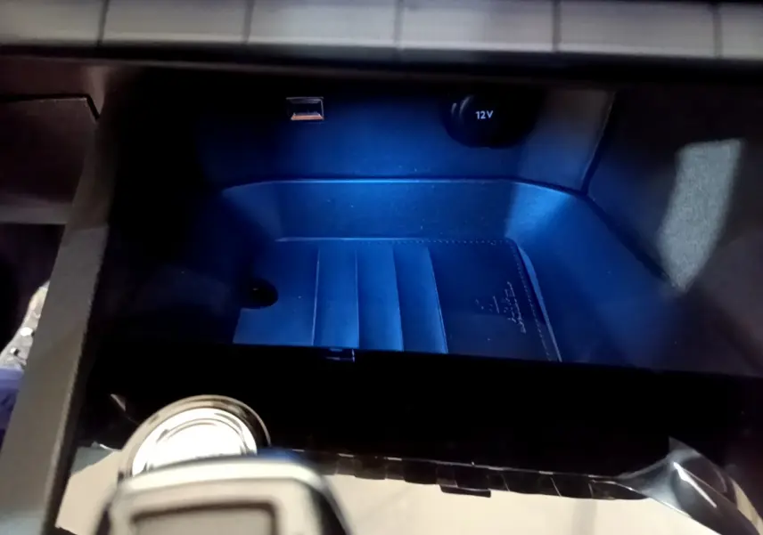 Gros plan sur la console centrale du Peugeot 5008 gris clair, avec prise 12V et port USB visibles.