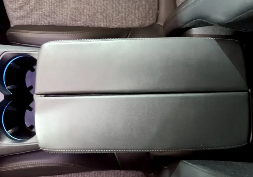 Vue plongeante sur l'accoudoir central en cuir noir et les porte-gobelets éclairés du Peugeot 5008 gris clair 2020.