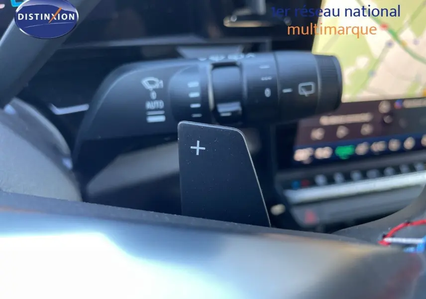Gros plan sur la palette de changement de vitesse + au volant d’un Renault Austral noir étoile métal, intérieur moderne.