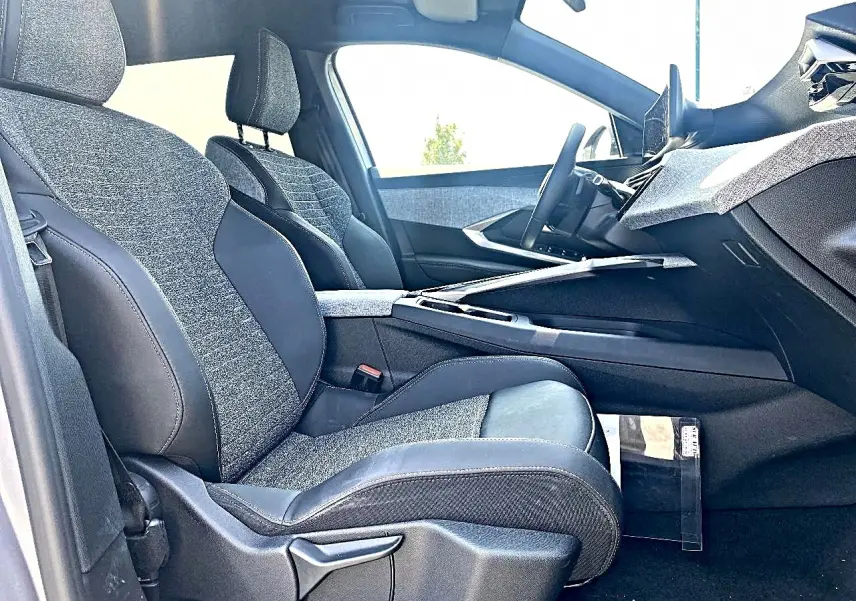 Vue intérieure côté conducteur du Peugeot 5008 Hybrid 145 allure e-dcs6, sièges tissu gris et cuir noir, tableau de bord moderne.