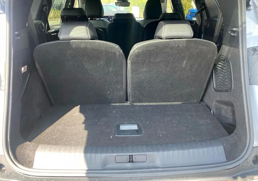 Vue arrière du coffre ouvert d’un Peugeot 5008 gris artense, montrant les sièges arrière relevés et l’espace de chargement.