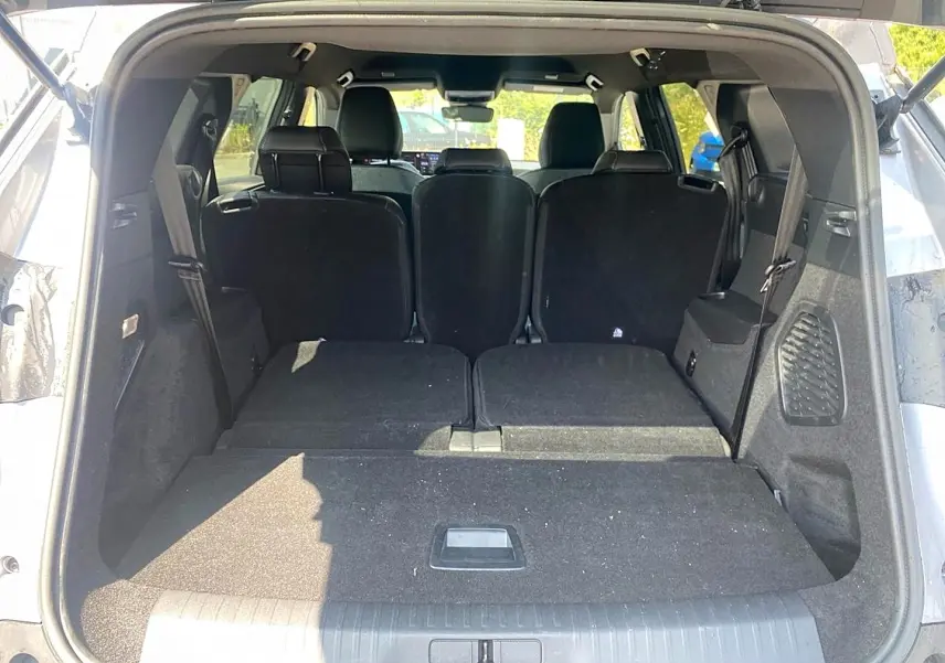 Coffre ouvert d’un Peugeot 5008 gris Artense, vue arrière montrant les sièges rabattus et l’espace de chargement plat.