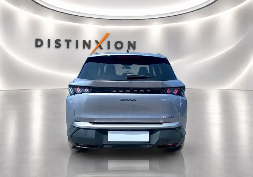 Vue arrière d’un Peugeot 5008 Hybrid 145 allure e-dcs6 gris artense avec feux LED et logo distinctif sur fond lumineux.