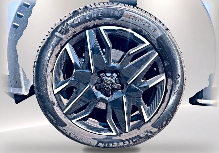 Gros plan sur la jante alu noire et argentée d’un Peugeot 5008 gris Artense, mettant en valeur le logo central Peugeot.