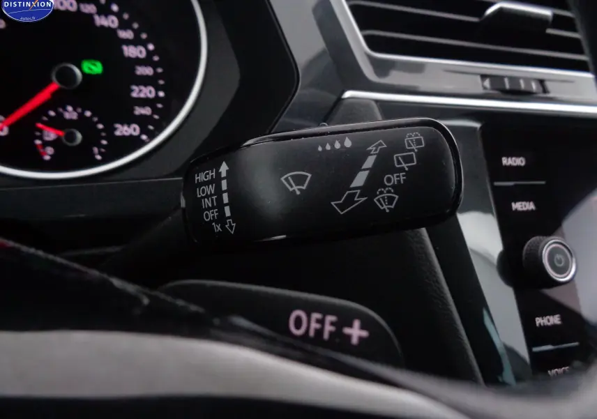 Gros plan sur la commande d'essuie-glace à gauche du volant dans l'habitacle noir du Volkswagen Tiguan blanc 2019.