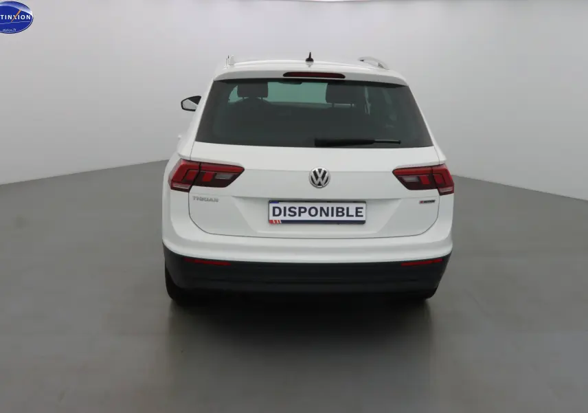 Vue arrière d'un Volkswagen Tiguan blanc 2019 avec logo VW et plaque "DISPONIBLE" dans un studio.