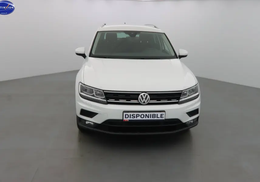 Vue frontale d'un Volkswagen Tiguan blanc 2019 avec calandre noire et feux LED allumés.