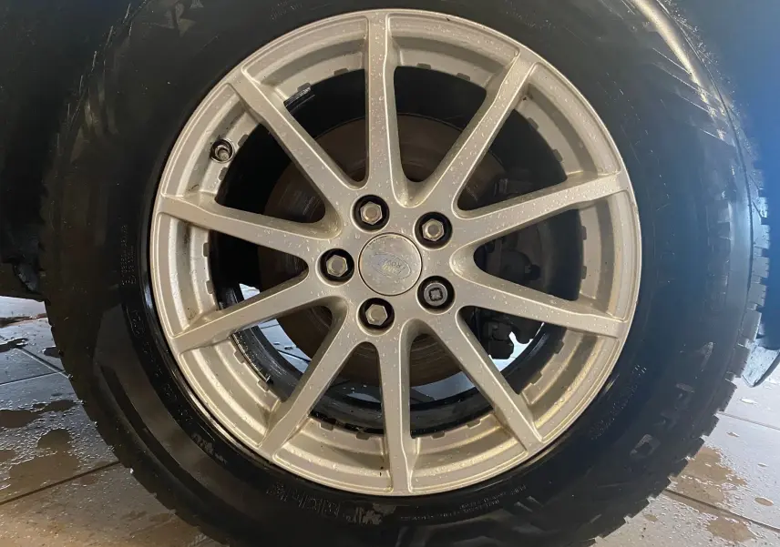 Gros plan sur la jante argentée à dix branches du Range Rover Evoque blanc, avec pneu tout-terrain visible.