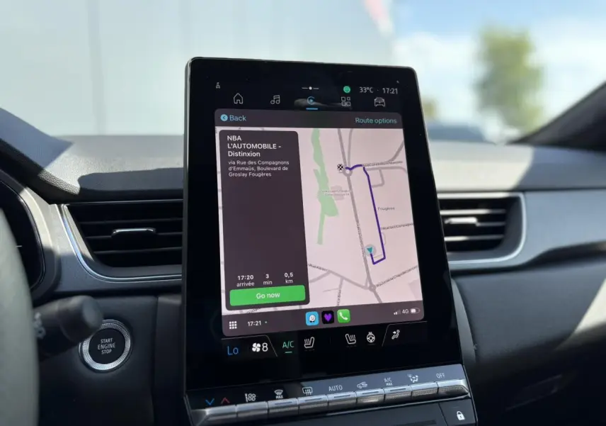 Écran tactile central du tableau de bord du Renault Captur 2025 affichant la navigation GPS et commandes climatisation.