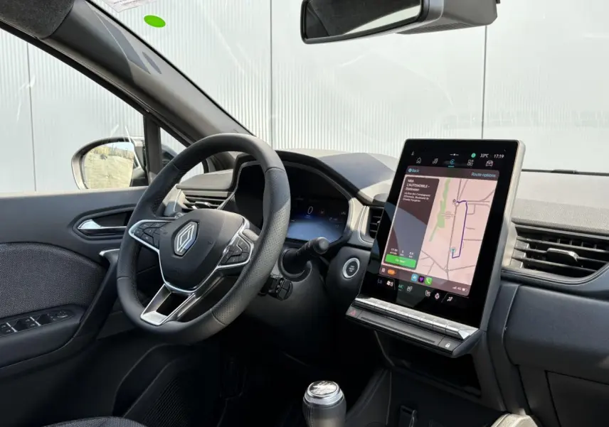 Intérieur du Renault Captur 2025 vu côté conducteur, volant multifonctions et écran tactile vertical avec navigation.