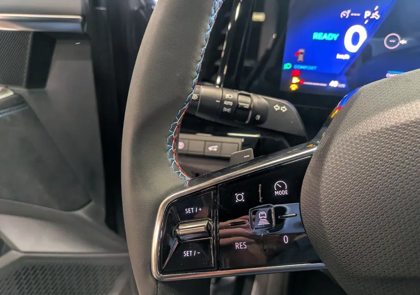 Gros plan sur le volant du Renault Austral gris Schiste Satin 2025, avec commandes intégrées et tableau de bord numérique bleu.