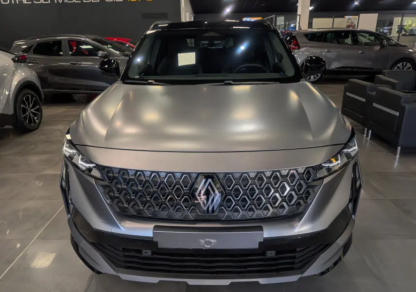 Vue de face du Renault Austral gris schiste satin avec toit noir, mettant en valeur sa calandre hexagonale distinctive en showroom.