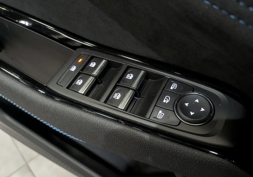 Gros plan sur les commandes des vitres électriques et rétroviseurs du côté gauche d'une Renault Austral gris Schiste Satin.