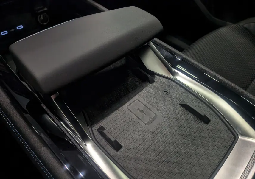 Détail de la console centrale du Renault Austral 2025 full hybride, avec surface de charge sans fil et accoudoir en cuir noir.