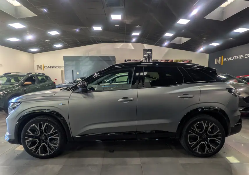 Profil droit du Renault Austral 2025 gris schiste satin avec toit noir et jantes noires distinctives en showroom.