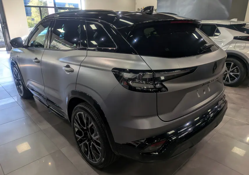 Renault Austral full hybride gris schiste satin avec toit noir, vue 3/4 arrière droit en intérieur showroom.