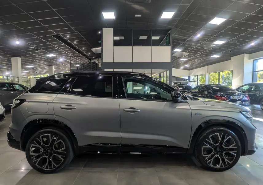 Renault Austral full hybride gris schiste satin avec toit noir, vue profil côté gauche en intérieur showroom.