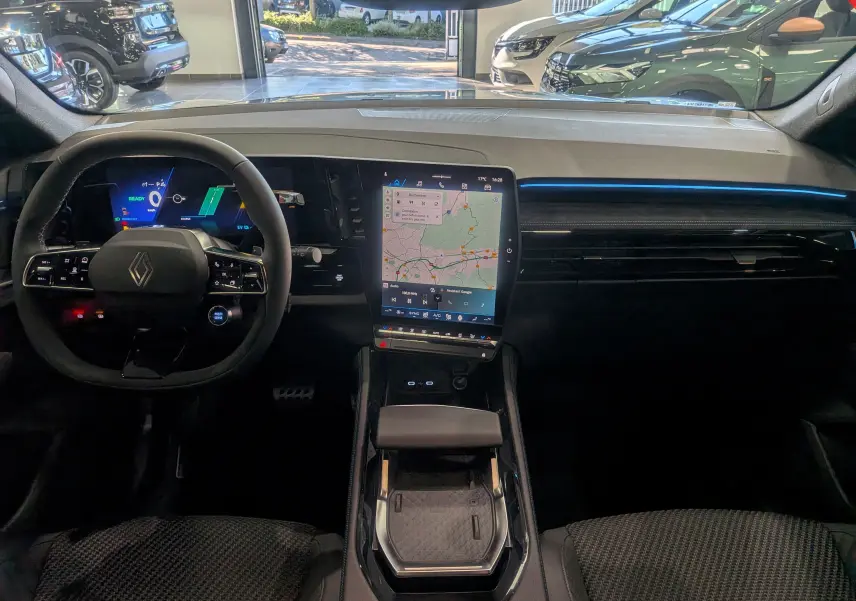Vue intérieure avant du Renault Austral hybride 2025, tableau de bord moderne avec écran tactile vertical et éclairage bleu fin.