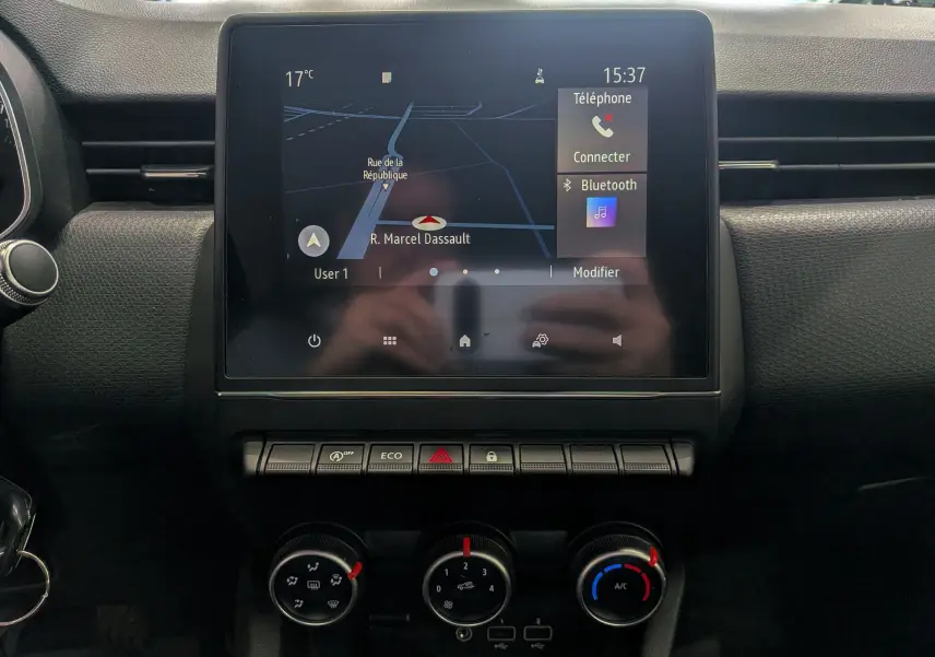 Écran tactile central avec navigation et commandes climatisation dans l'habitacle d'une Renault Clio V blanche.