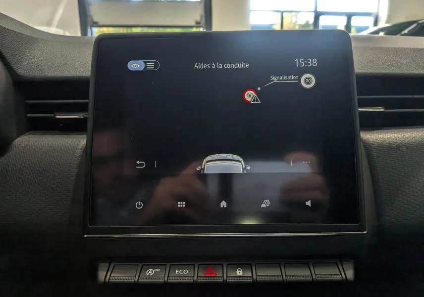 Écran tactile central du tableau de bord de la Renault Clio V blanc glacier, affichant l'aide à la conduite et la signalisation.
