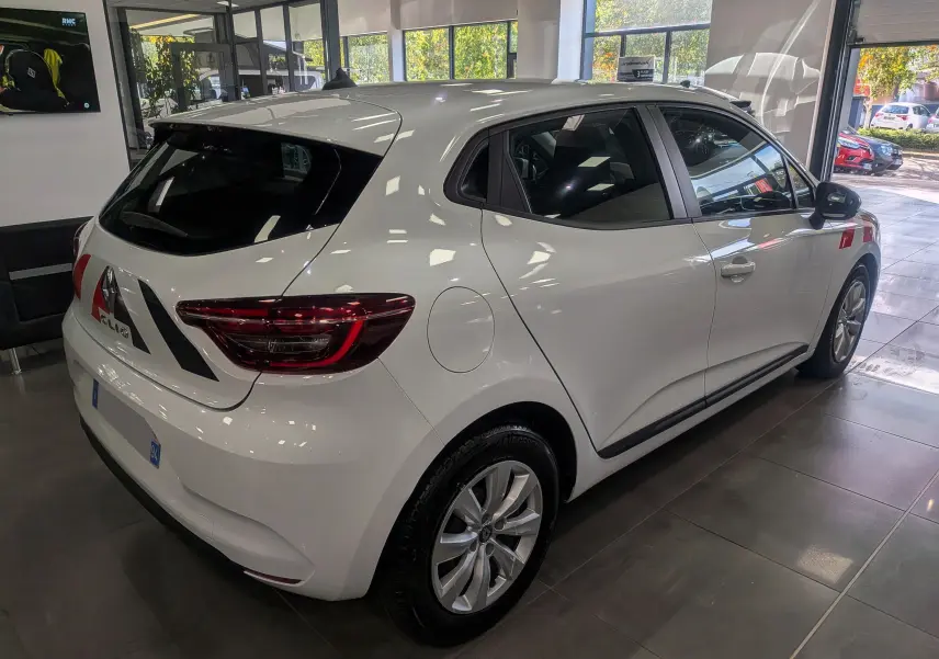 Vue de profil côté droit d'une Renault Clio V blanche Glacier en intérieur, avec marquages rouges sur la porte.