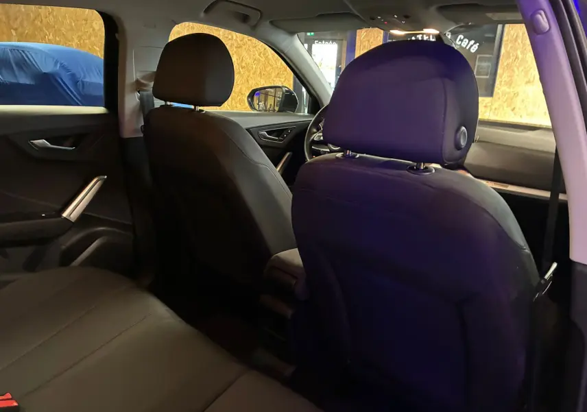 Vue intérieure arrière de l'Audi Q2 noir 2023, montrant les sièges avant et arrière en tissu noir dans un habitacle spacieux.