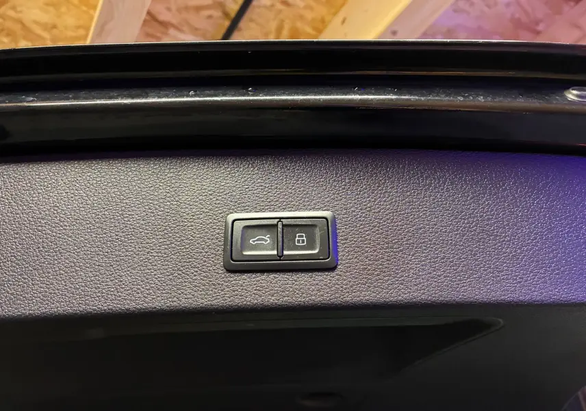 Boutons d'ouverture et de verrouillage du coffre sur la garniture intérieure noire d'un Audi Q2 35 TFSI S-Line 2023.