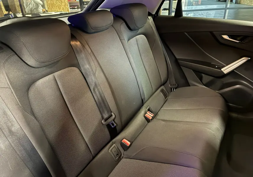 Vue intérieure côté droit des sièges arrière noirs en tissu de l'Audi Q2 35 TFSI S-Line 2023 avec ceintures et appuie-têtes.